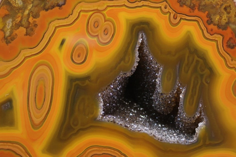 Lilangabi agate 108 mm – close-up of double eye, druzy vug cavity and scalloped fortification banding, vivid tangerine-orange chromatism | SKU LIL00010