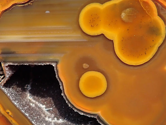 Lilangabi agate 66 mm – close-up, agate eyes, waterlines, goethite needles in vug, fiery amber-orange palette