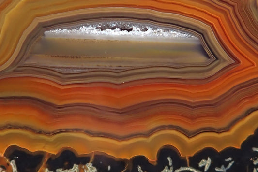 Lilangabi agate 63 mm – close-up of waterline centre and drusy vug, chromatism, fortification banding, amber and sard-carnelian tones, Eswatini