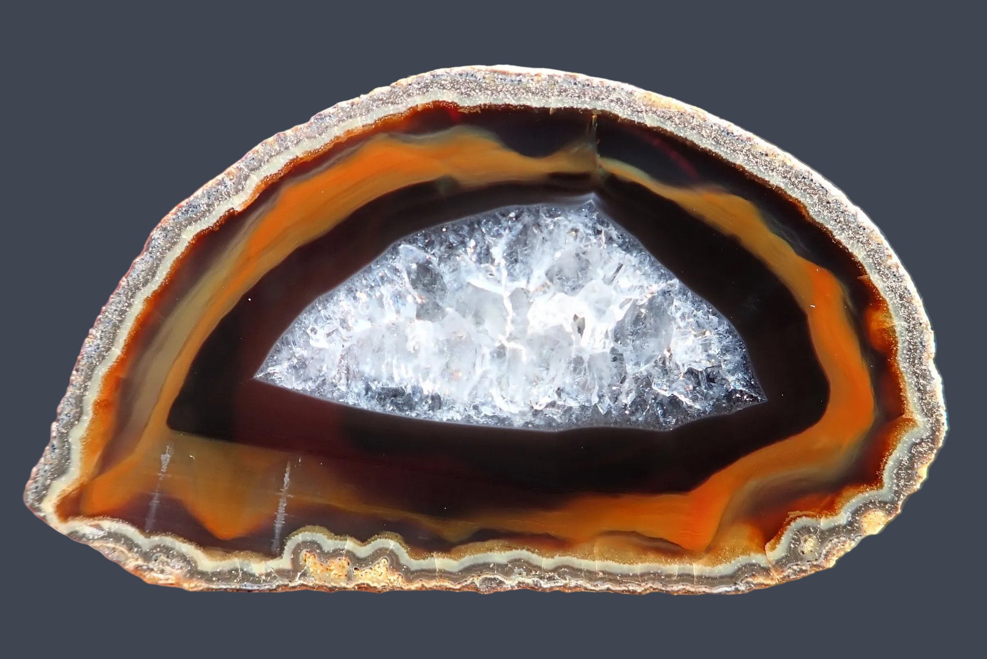 Lilangabi agate 67 mm – front face, chromatography, deep amber and burnt orange bands transitioning to near-black and blue-grey crystalline centre