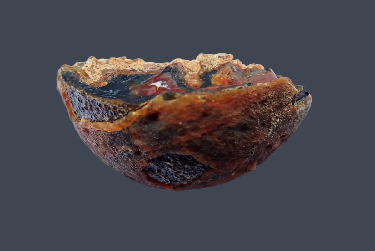 Lilangabi agate 71 mm, back view showing curved brown natural rind with dark exposed patches and an orange band along the cut edge, Lebombo Mountains.