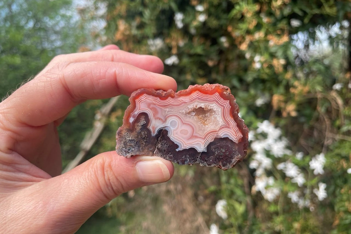 Malawi agate 57 mm – size reference in hand, scalloped banding in terracotta and cream, Ngabu Malawi