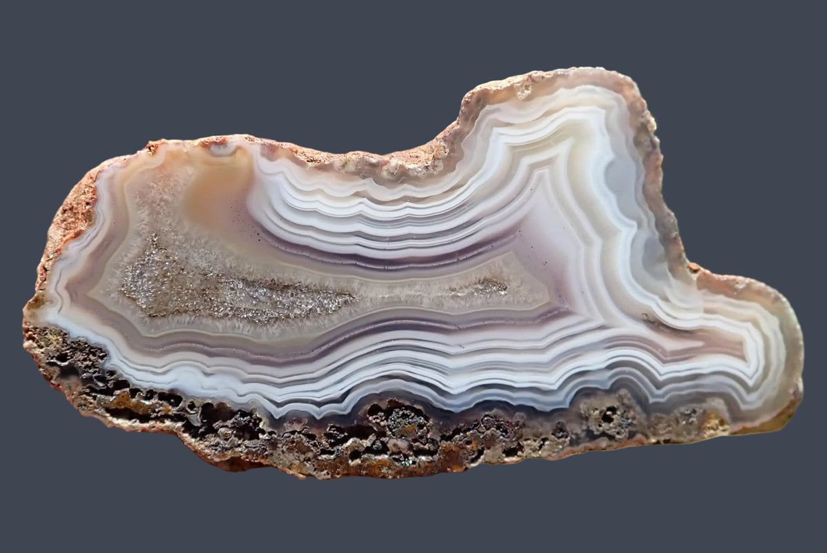 Malawi agate 70 mm, polished face with white, grey and pale mauve bands, ghost banding and shiny calcite in an elongated crystalline centre, Ngabu, Malawi.