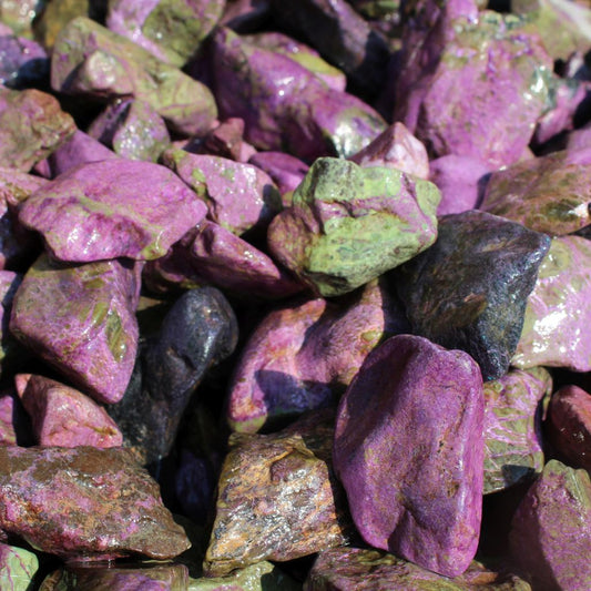 Wet natural stichtite rough specimens in serpentine matrix, Kaapsehoop, South Africa — bulk lot showing pink to purple colour range, wet finish | SKU STICHRsml