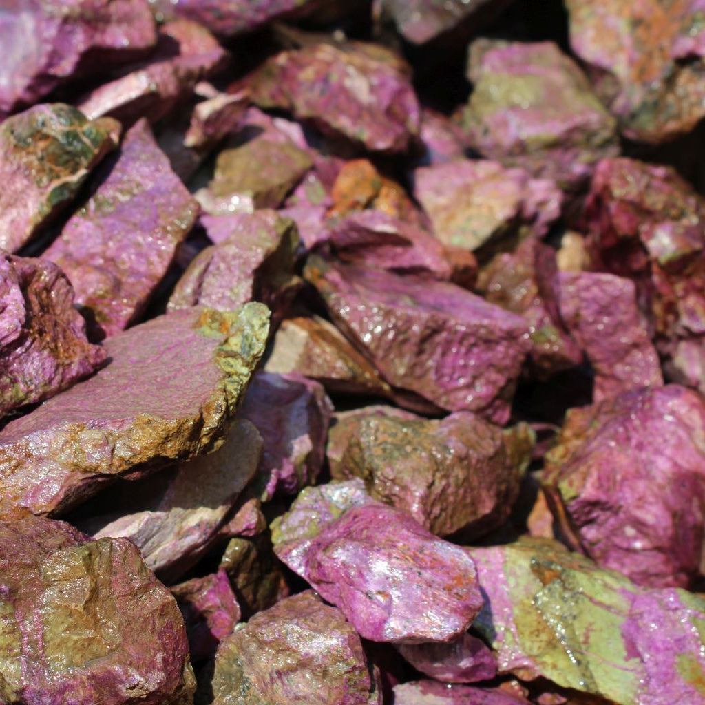 Wet natural stichtite specimen grade large rough in serpentine matrix, Kaapsehoop, South Africa — bulk lot showing pink-purple to green serpentine colour range, wet finish | SKU STICHSPEC