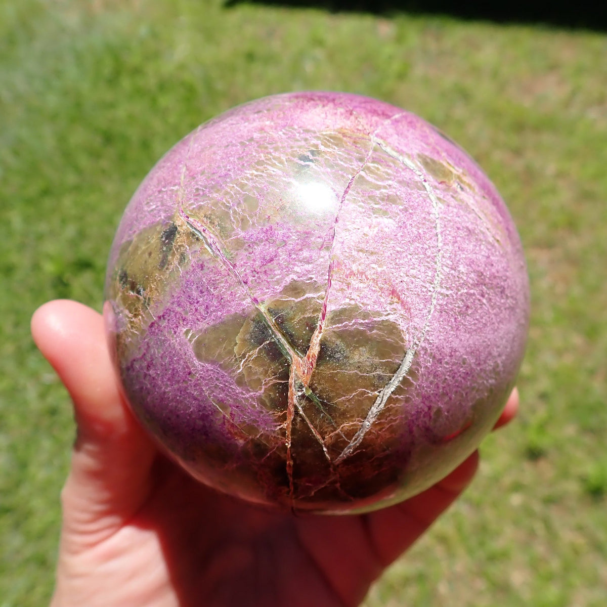 Stichtite with Serpentine sphere showing angular olive-brown patches and intersecting pale veins within pink-purple intergrowths.