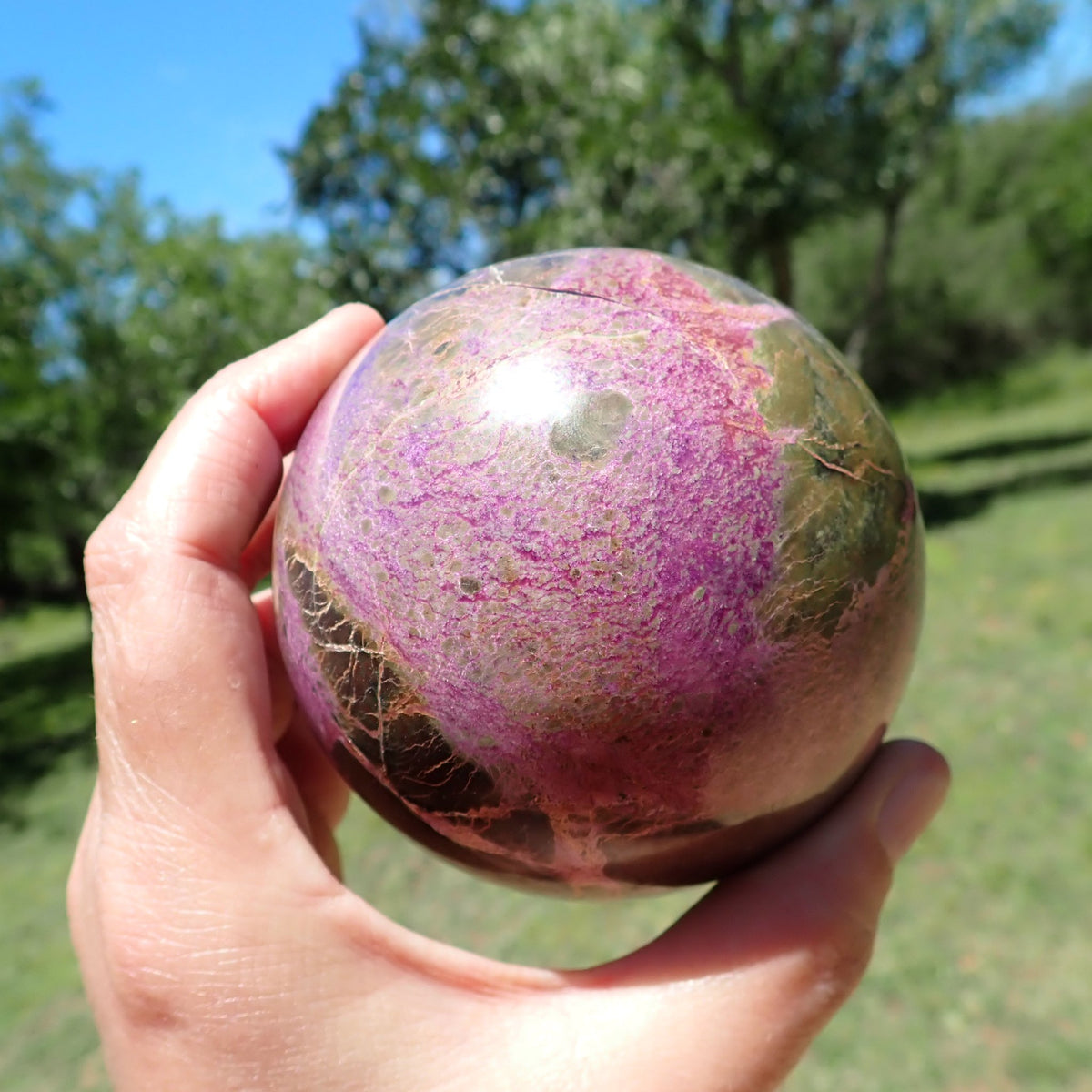 Stichtite with Serpentine sphere showing pink-purple intergrowths bordered by olive-green and dark brown patches.