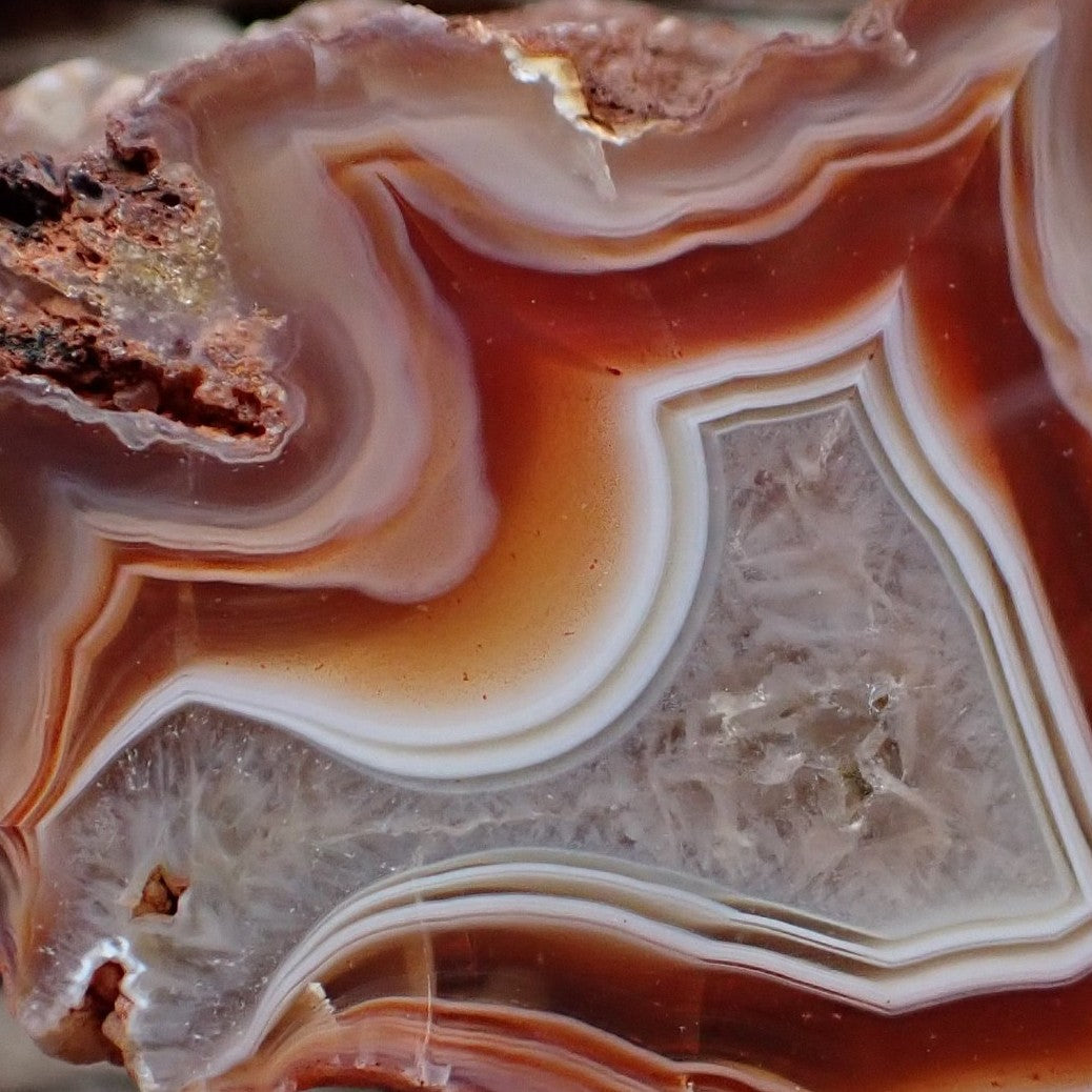 Close-up of Malawi agate 46 mm – star-form inner zone detail, flow channel, amber-orange transition band and pale grey-lavender micro-crystalline centre | SKU 000343