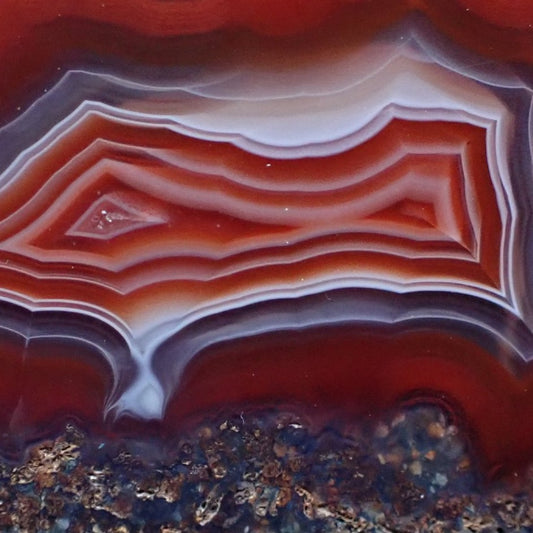 Close-up of a Malawi agate with bold red and ghost banding exiting into a flow channel