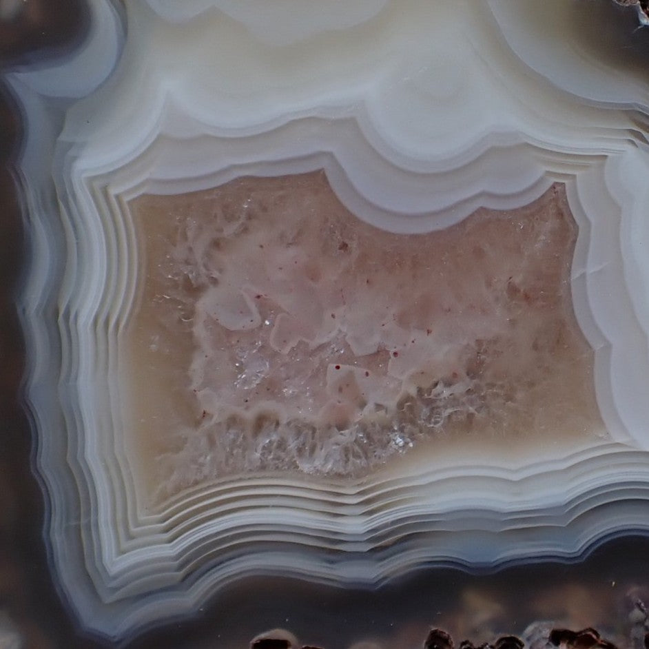 Detail of centre, natural hand-polished Malawi agate 52 mm – scalloped inner bands, ghost banding, warm blush-buff crystalline centre, Ngabu origin | SKU 000392