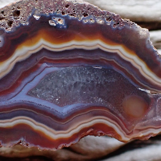 close up of Ngabu achat with eye and flow channels and crystalline centre surrounded by blue and red bands