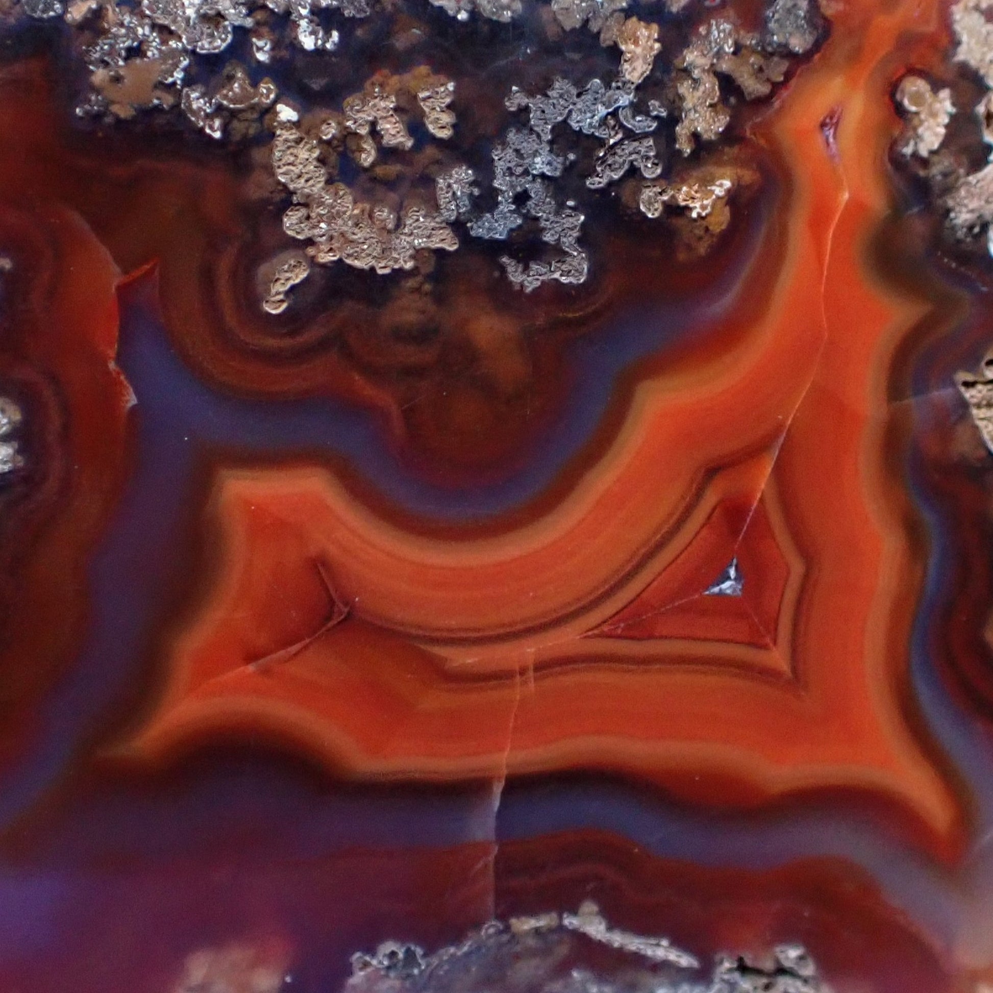 Close-up of a colorful polished malawi ngabu agate with layered patterns in orange and purple