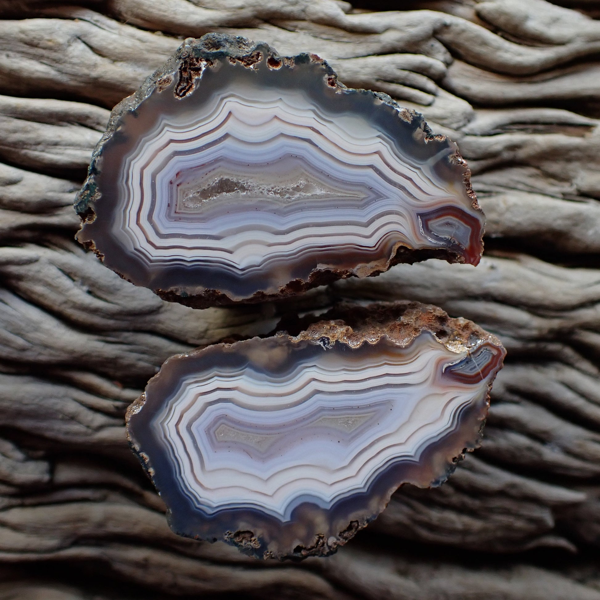 Stunning matching pair of Malawi ngabu agates with fortification banding in swirls of cream white and grey-blue going into a crystalline centre, both have matching flow channels