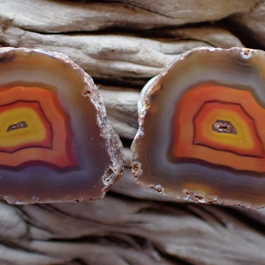Close-up of two agate stones with concentric color patterns on a wooden background.