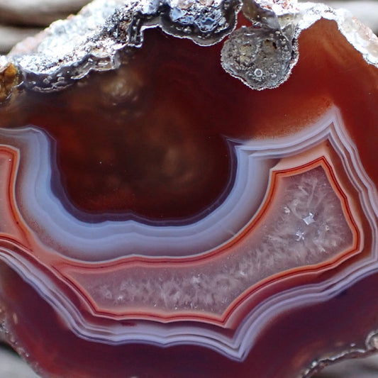 close up of a Malawi Ngabu agate crystalline centre surrounded by a right peach line going into ghost banding