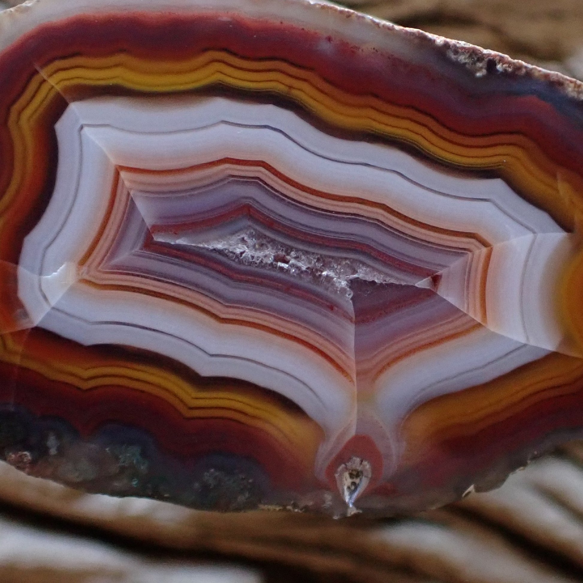 Close-up of a multicolored Malawi Ngabu agate stone with concentric layers, a flow channel and fortification banding