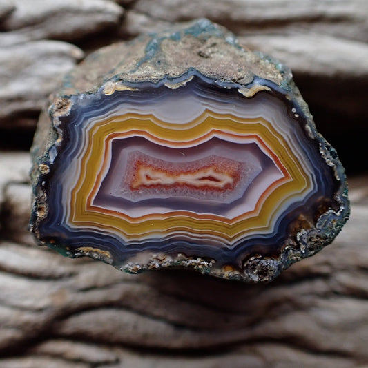 Polished Malawi Agate with sharp concentric banding. Features vibrant layers of royal purple, gold, and blue, formed over millions of years