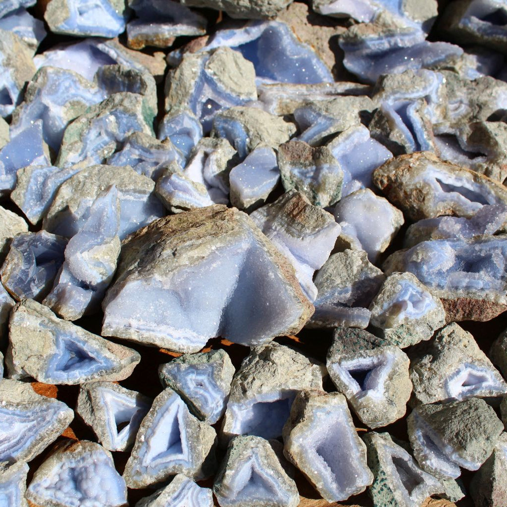 Wholesale Blue Lace Agate rough from Malawi – close overhead view of selected specimens with visible vug cavities and Tyndall-effect blue coloration, natural rough finish | SKU BLAperkg