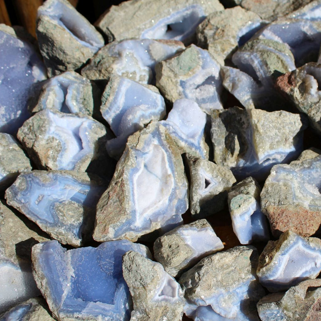Wholesale Blue Lace Agate rough from Malawi – close-up of pale blue chalcedony pieces with druzy sparkle and natural fracture faces, basalt matrix visible | SKU BLAperkg