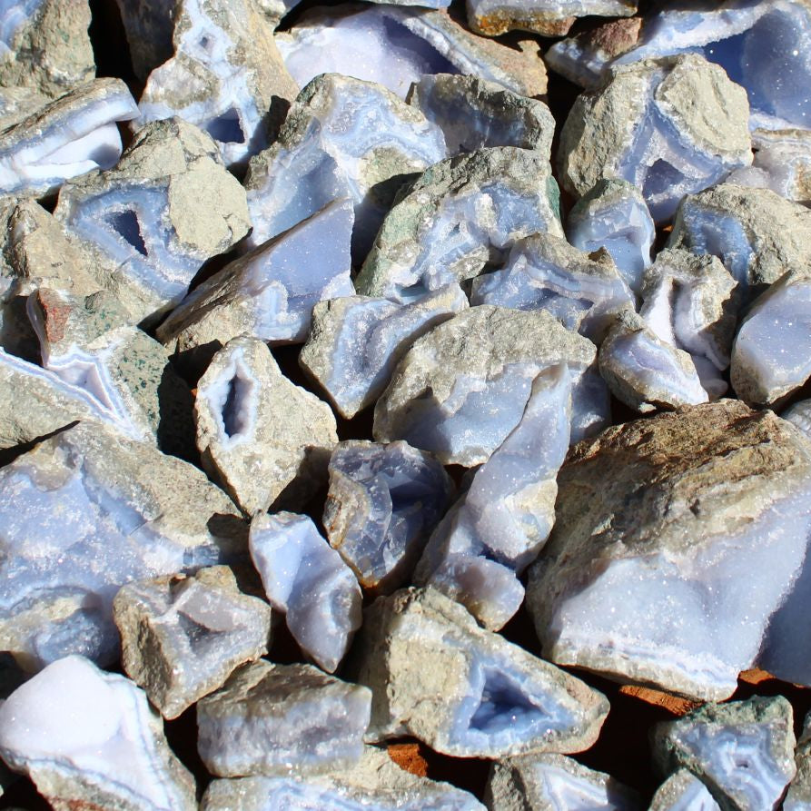 Wholesale Blue Lace Agate rough specimens from Nsanje, Malawi – sunlit group showing fortification banding and variable blue-white coloration, natural rough finish | SKU BLAperkg