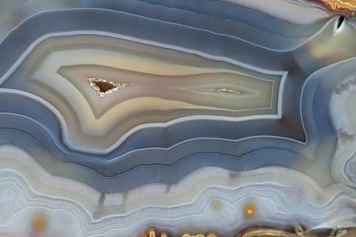 Ghost Mountain agate 122 mm – detail of concentric banding, chromatography colour shift, tiny drusy vug, cream and steel-blue layers
