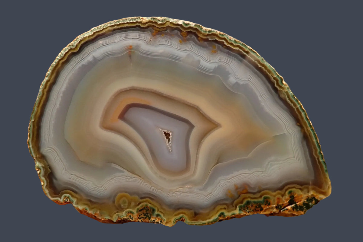 Ghost Mountain agate 80 mm – close-up face, sweeping concentric banding in white, grey and amber, drusy vug centre, South Africa