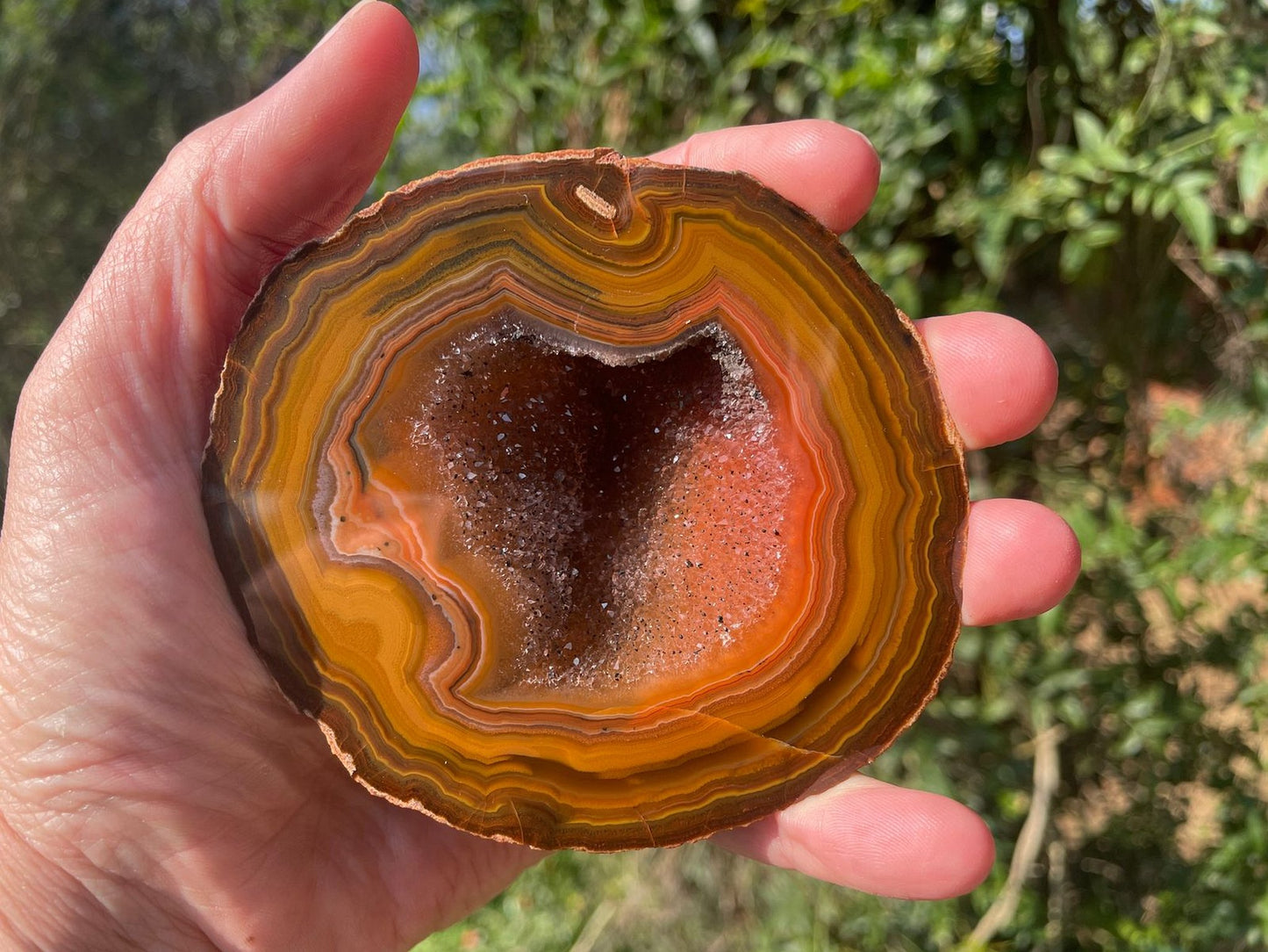 Lilangabi agate 94 mm – in-hand size reference, concentric banding and open druzy vug visible | SKU LIL00001