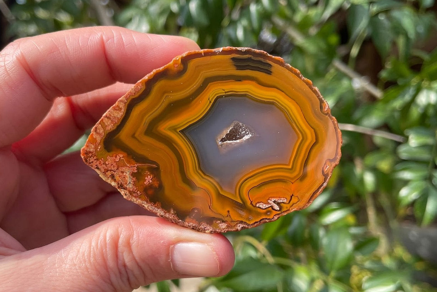 Lilangabi agate 68 mm – in-hand size reference, plume inclusion bottom left, flow channel