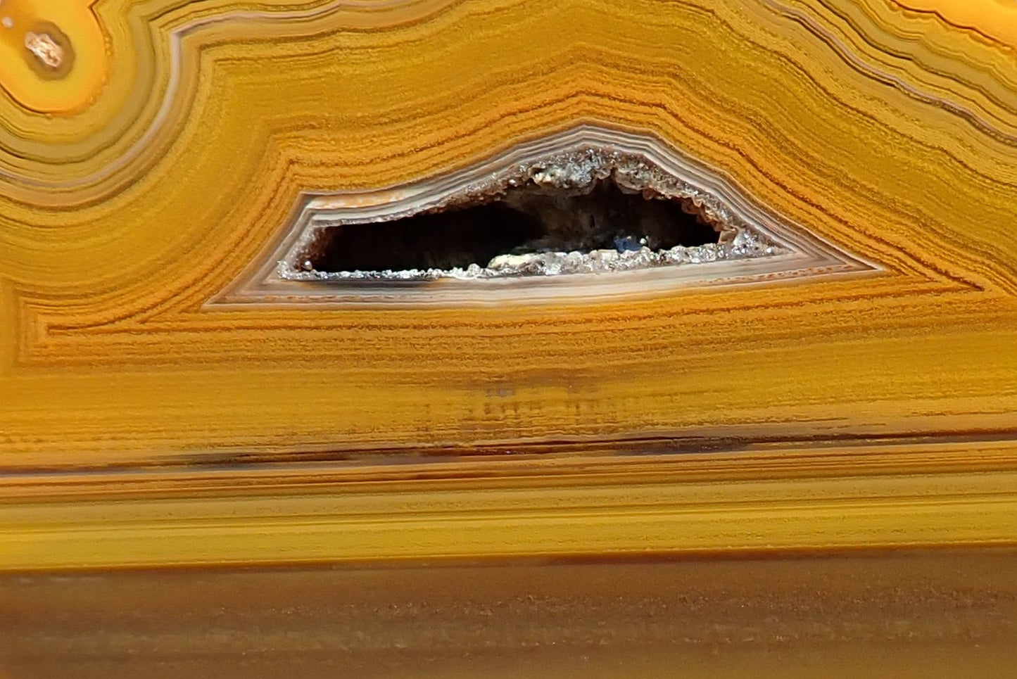 Lilangabi agate 86 mm – close-up of fortification banding and triangular drusy vug, honey and caramel tones