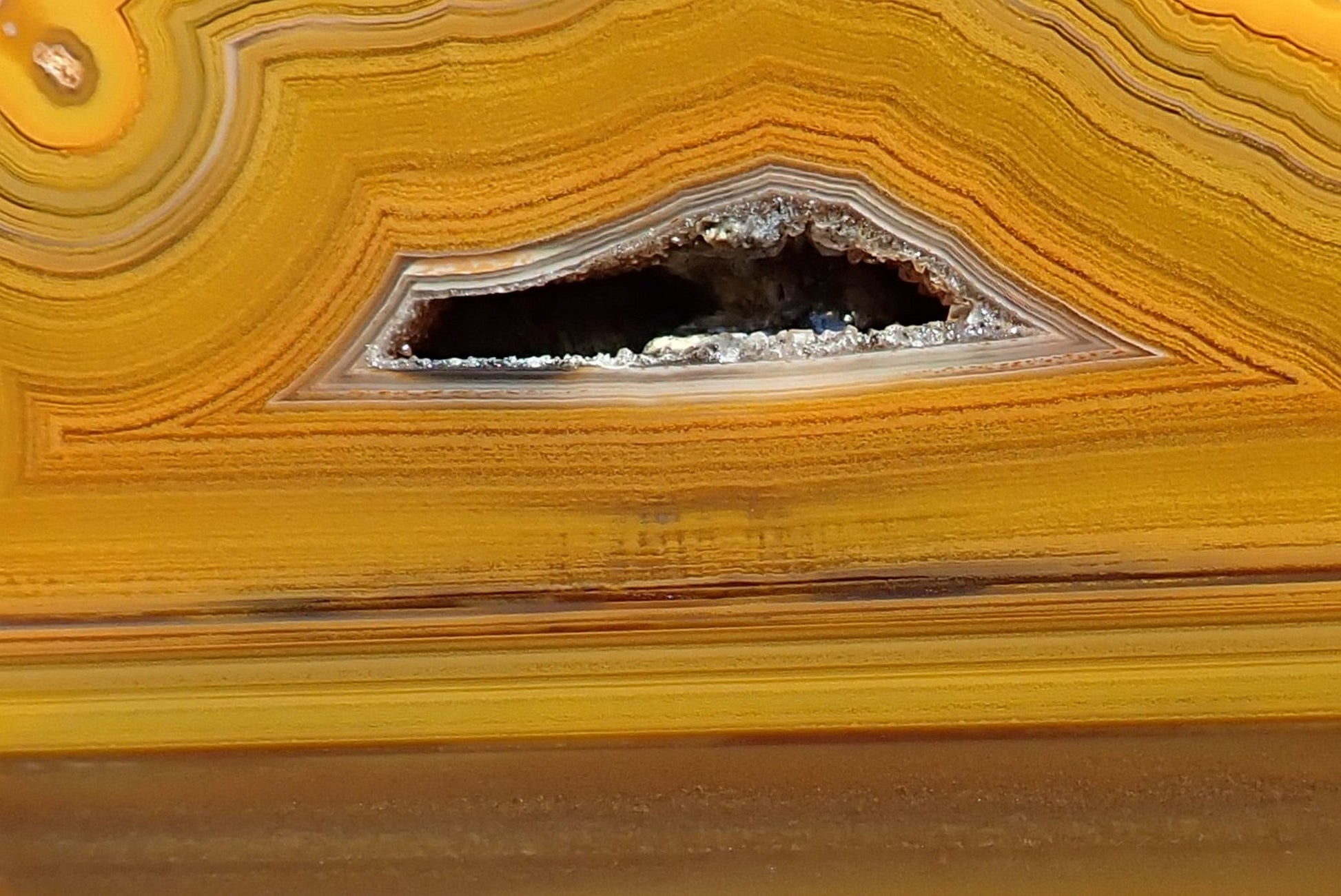 Lilangabi agate 86 mm – close-up of fortification banding and triangular drusy vug, honey and caramel tones