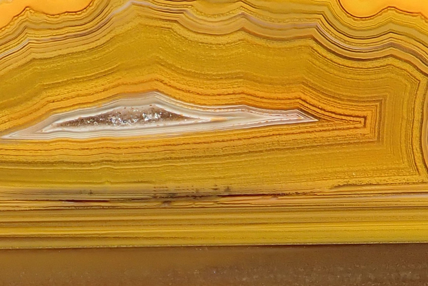 Lilangabi agate 87 mm – close-up of fortification banding and lens-shaped vug, pale chalcedony halo