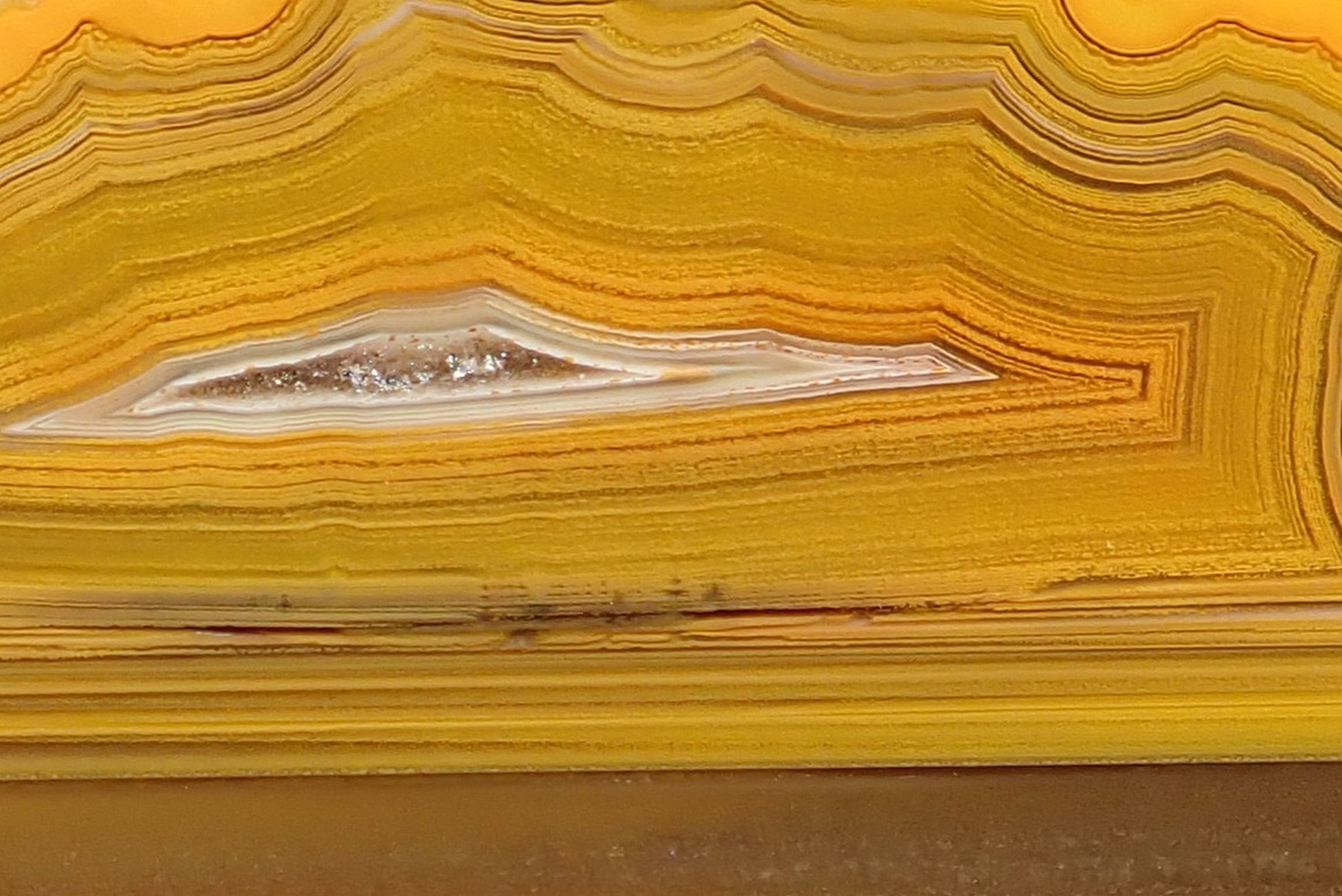 Lilangabi agate 87 mm – close-up of fortification banding and lens-shaped vug, pale chalcedony halo