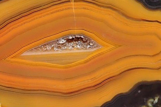 Lilangabi agate 71 mm – face detail, chromatography banding, drusy vug with pale chalcedony and crystal fill, golden amber to near-black