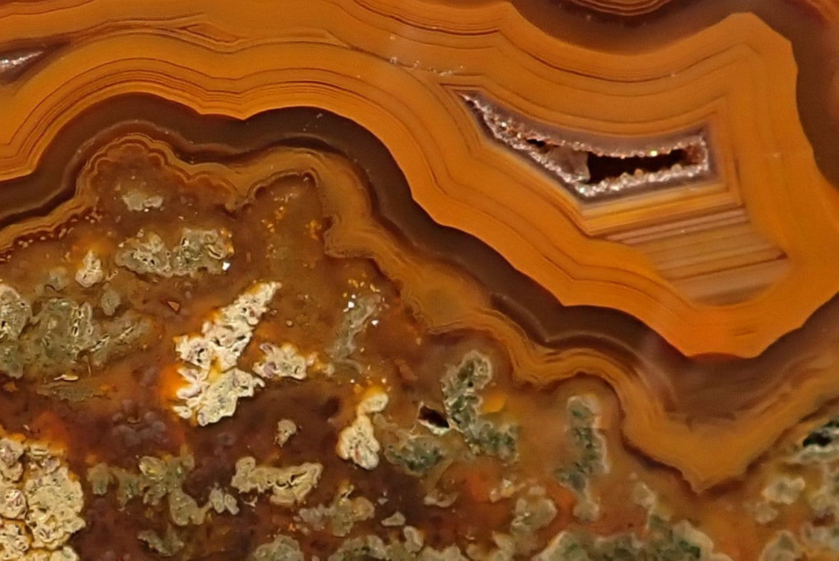 Lilangabi agate 102 mm – close-up, scalloped banding with chromatographic shift, rectangular drusy vug with exposed crystal structure