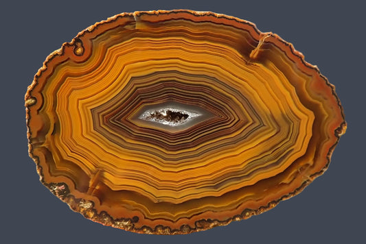Lilangabi agate 71 mm – face view, dense fortification banding, chromatographic shift from golden amber to deep orange-brown, drusy vug centre, Lebombo Mountains