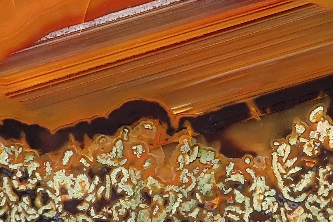 Lilangabi agate 77 mm – close-up of closely spaced amber waterlines and the intricate cream-and-dark lower patterning.