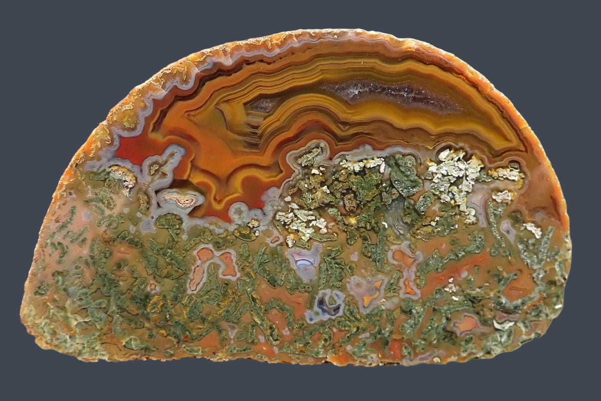 Lilangabi agate 72 mm, full face showing golden-amber fortification banding and chromatography around a smooth purple amethyst section, with green moss inclusions and small agate chambers below.