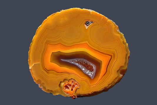 Lilangabi agate 49 mm, golden-yellow fortification banding with an orange inner band surrounding a dark brown centre and elongated crystal-lined drusy vug.