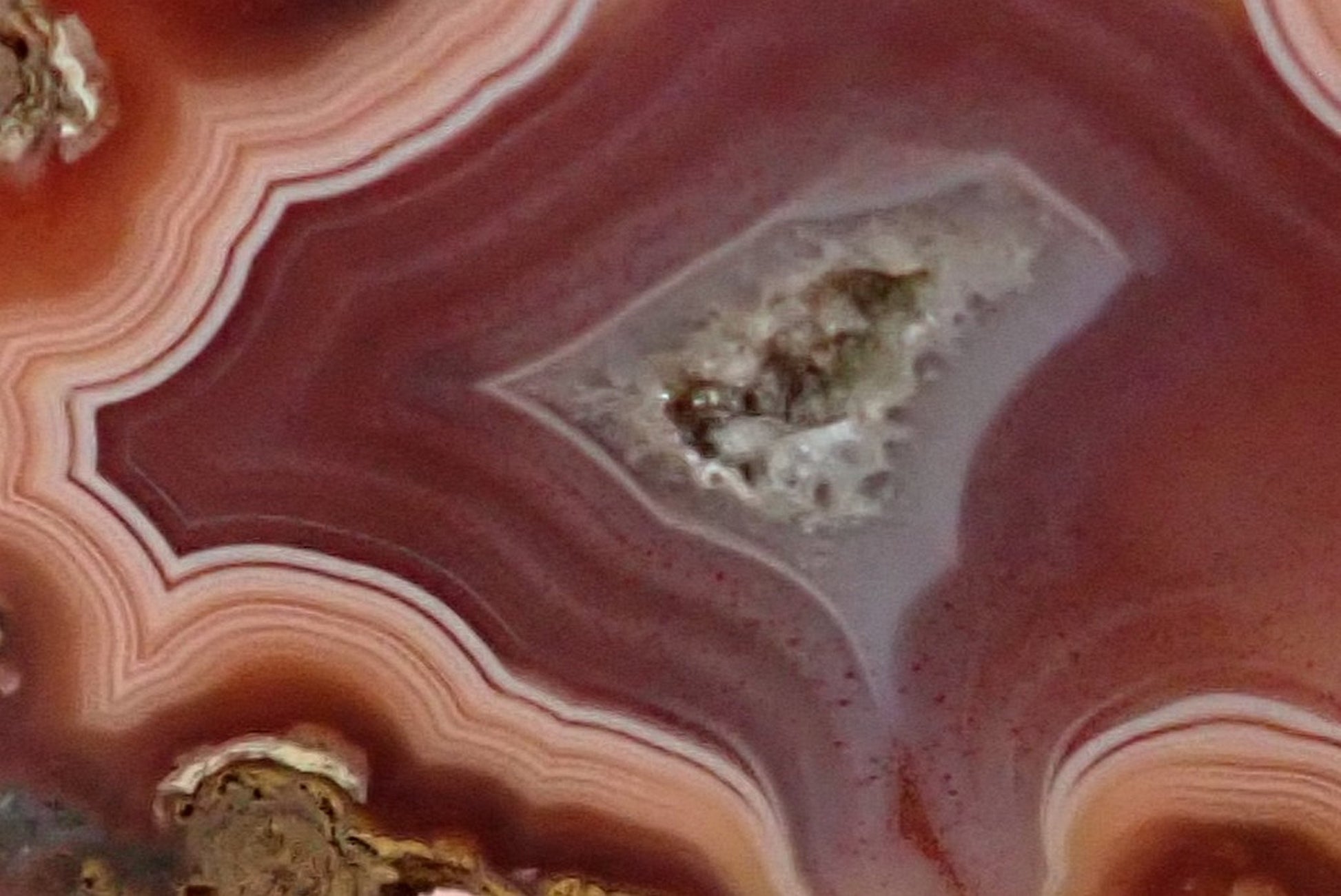 Malawi agate 40 mm – face detail, angular fortification bands, flow channel, drusy vug with calcite crystal, burgundy to rose-pink