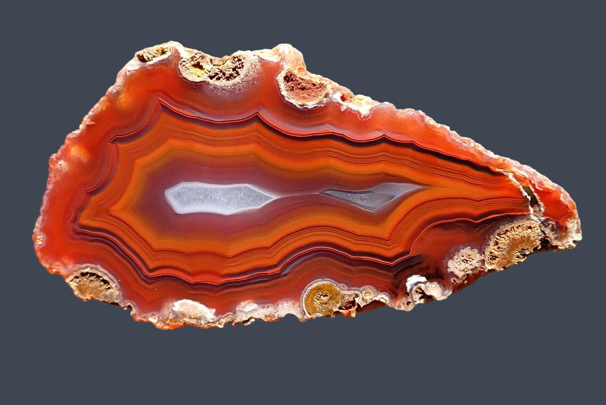 Malawi agate 57 mm, polished face with orange-red fortification banding, thin dark outlines, purple-grey inner layers and two pale crystalline centres, Ngabu.