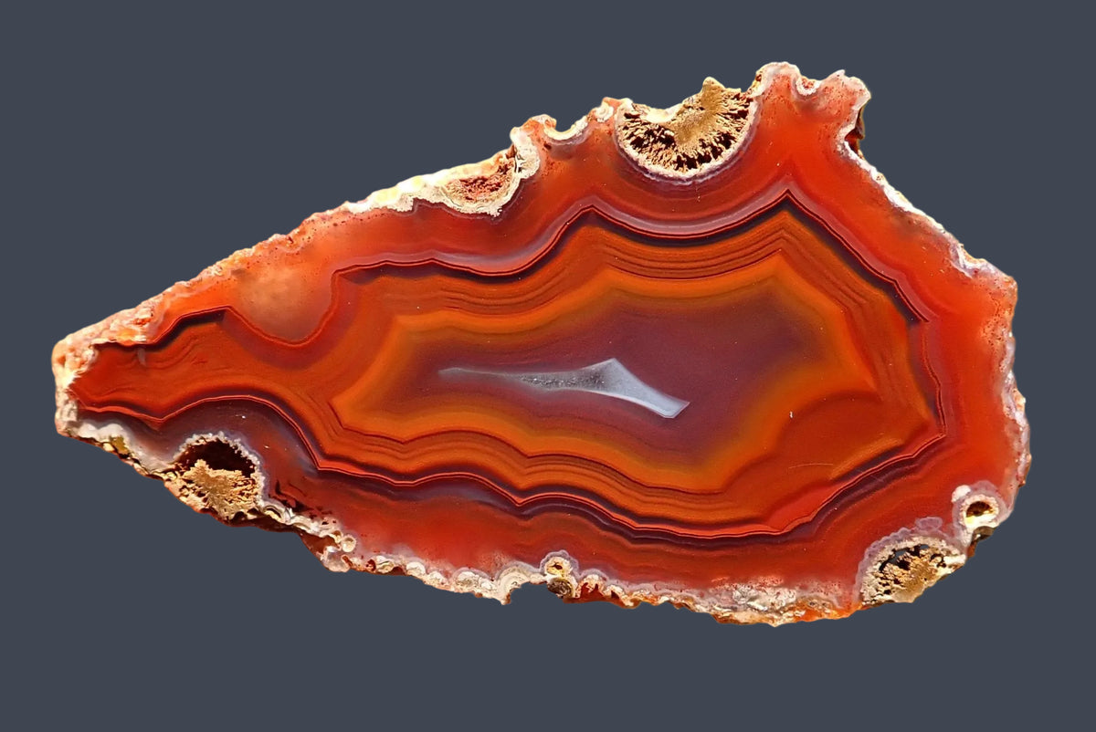Malawi agate 55 mm, polished face showing orange-red fortification banding with fine dark outlines around a purple-grey centre and a narrow pale crystalline section, Ngabu.