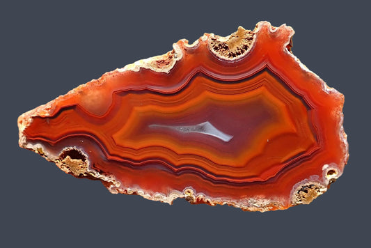 Malawi agate 55 mm, polished face showing orange-red fortification banding with fine dark outlines around a purple-grey centre and a narrow pale crystalline section, Ngabu.