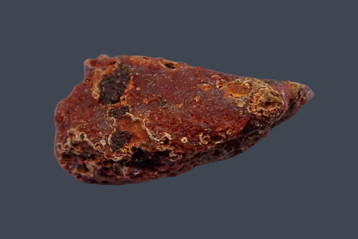 Malawi agate 55 mm, unpolished back showing a rough reddish-brown exterior with small cavities and tan patches, Ngabu.