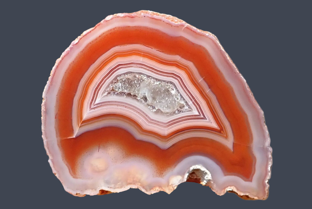 Malawi agate 38 mm – hand-polished face with fine white, pale pink and red-orange fortification banding around a drusy centre containing calcite, with hematoid speckling, Ngabu.