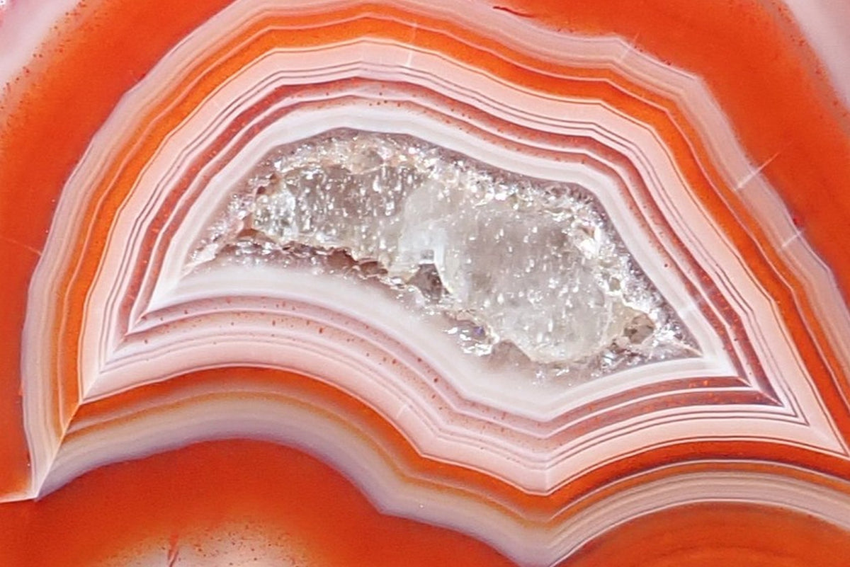 Malawi agate 38 mm – detail of the drusy centre with calcite, framed by tightly nested angular bands in white, pink and red-orange with fine hematoid spots, Ngabu.
