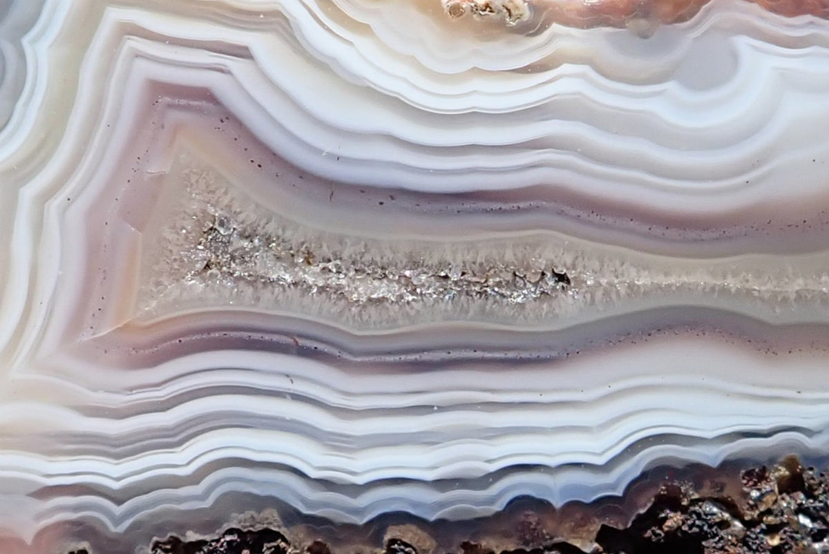 Malawi agate 66 mm, crystalline centre detail with ghost banding and closely spaced white, grey and pale mauve bands, Ngabu, Malawi.