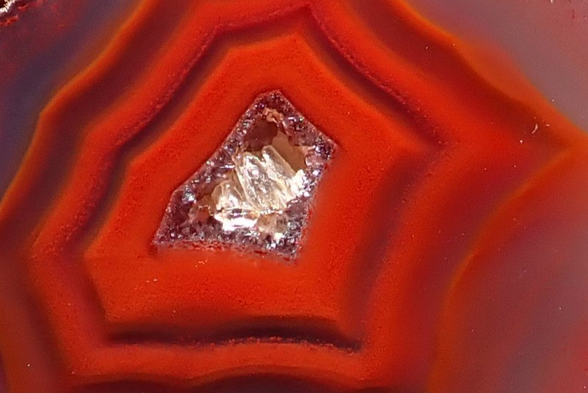 Malawi agate 41 mm – close-up of the crystalline centre and angular red-orange fortification bands with shadow banding, Ngabu.