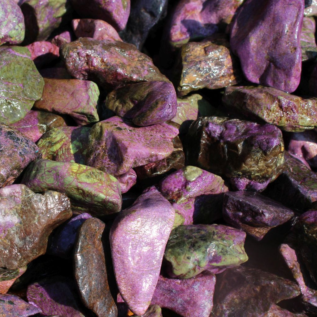 Wet natural stichtite rough specimens in serpentine matrix, Kaapsehoop, South Africa — bulk lot showing pink to purple colour range, wet finish | SKU STICHRsml