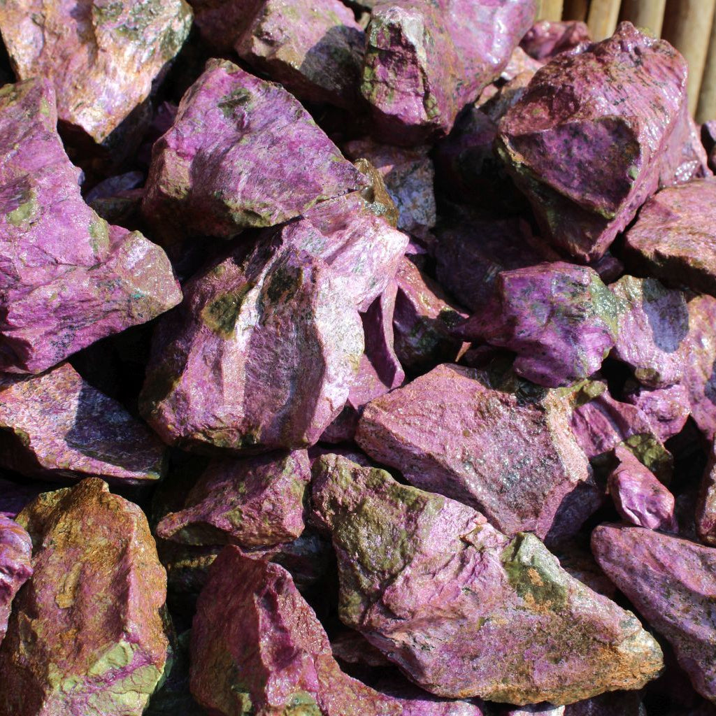 Wet natural stichtite specimen grade large rough in serpentine matrix, Kaapsehoop, South Africa — bulk pile showing size range and colour variation, wet finish | SKU STICHSPEC