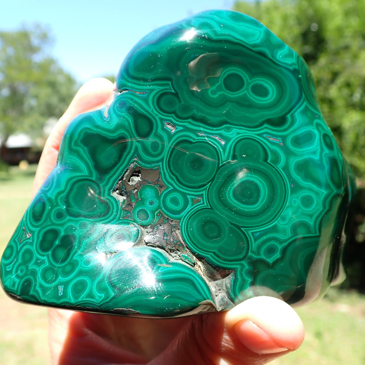 Malachite polished freeform narrow side showing tightly spaced green rings and curved banding